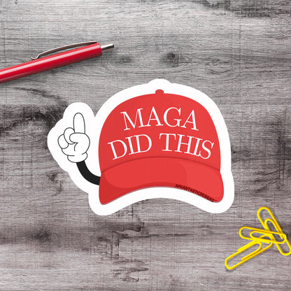 a sticker with a red baseball cap and the text "MAGA DID THIS" on a wooden surface.