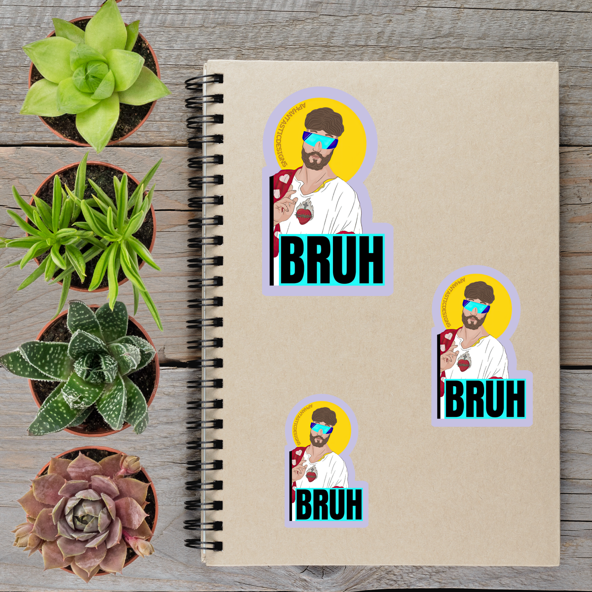 a spiral notebook with stickers on it, along with several potted plants arranged on a wooden surface.