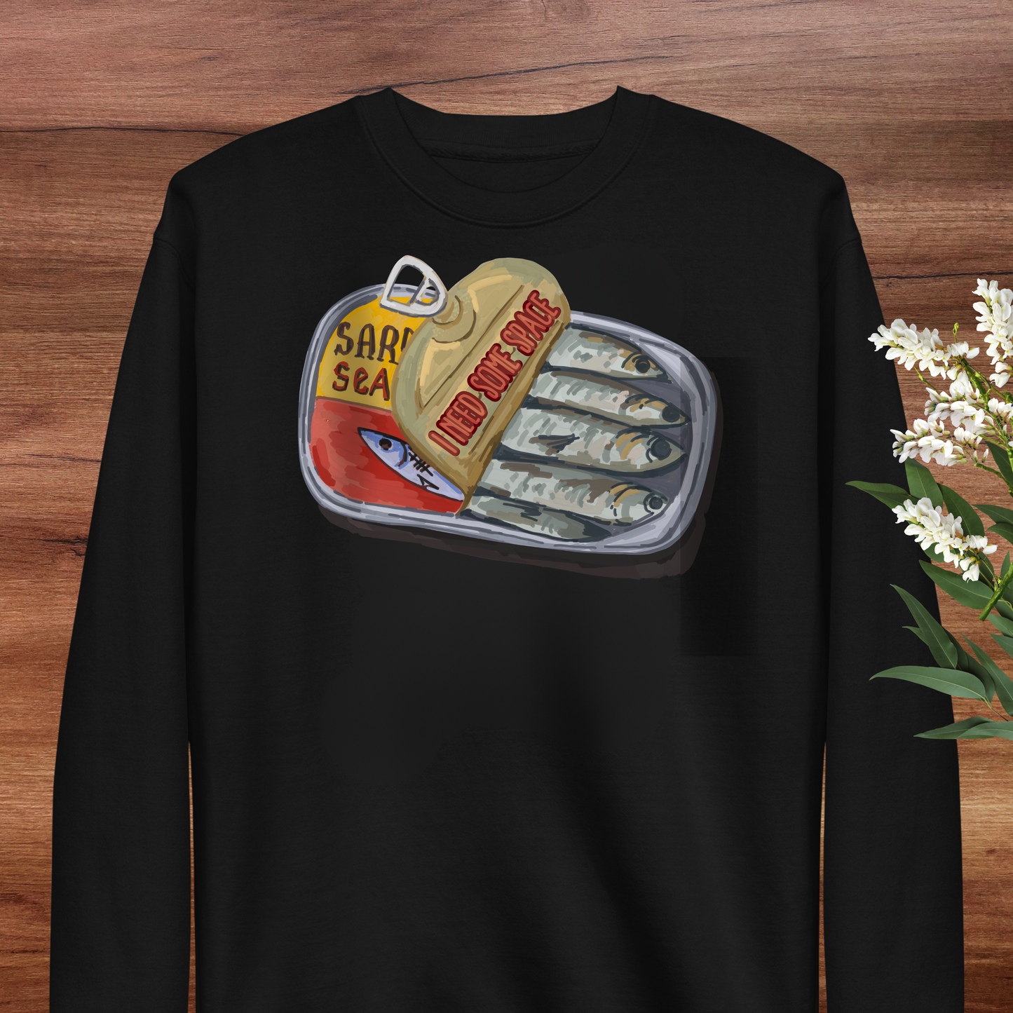 A black long-sleeved shirt with a graphic design depicting a can of sardines and a yellow container with the text "I ADD SARDINES" printed on it.
