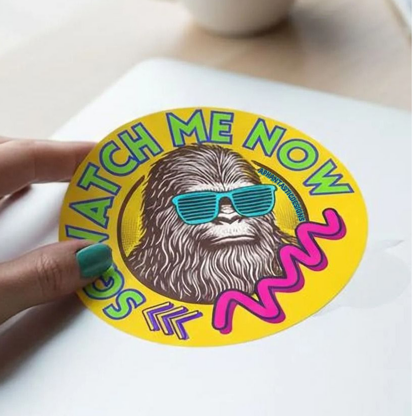 A sticker featuring a cartoon character wearing sunglasses and the text "WATCH ME NOW" in a colorful, retro-style design.