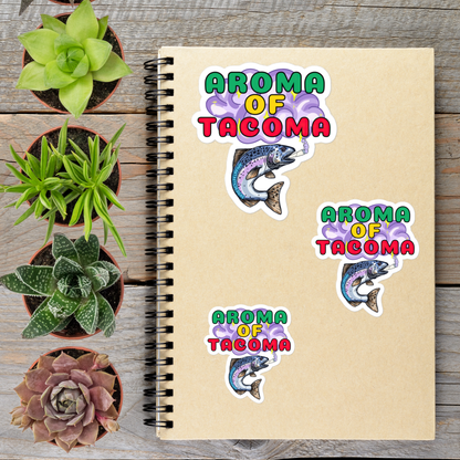 a spiral notebook with stickers on it, surrounded by potted plants on a wooden surface.