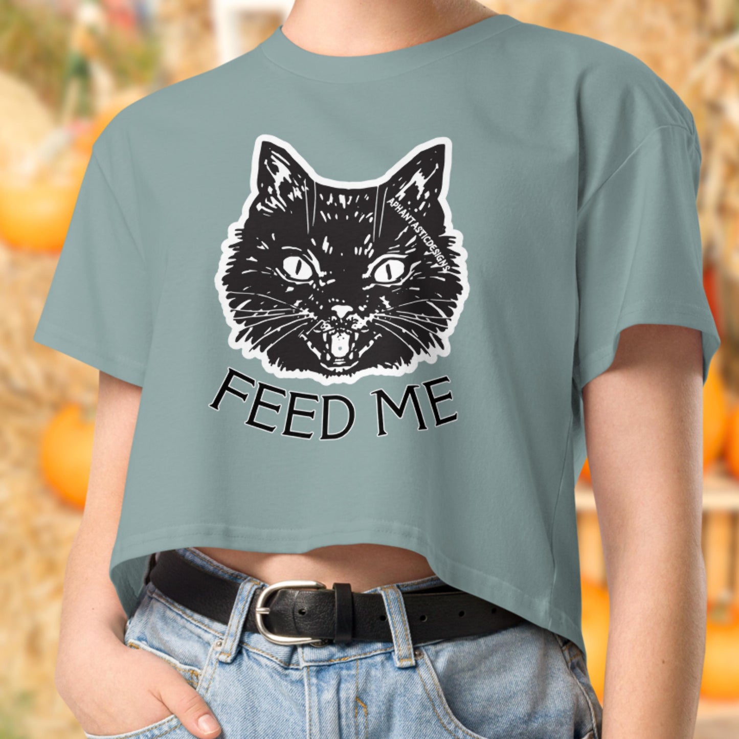 A person wearing a green crop top with a graphic of a cat and the text "FEED ME" printed on it.