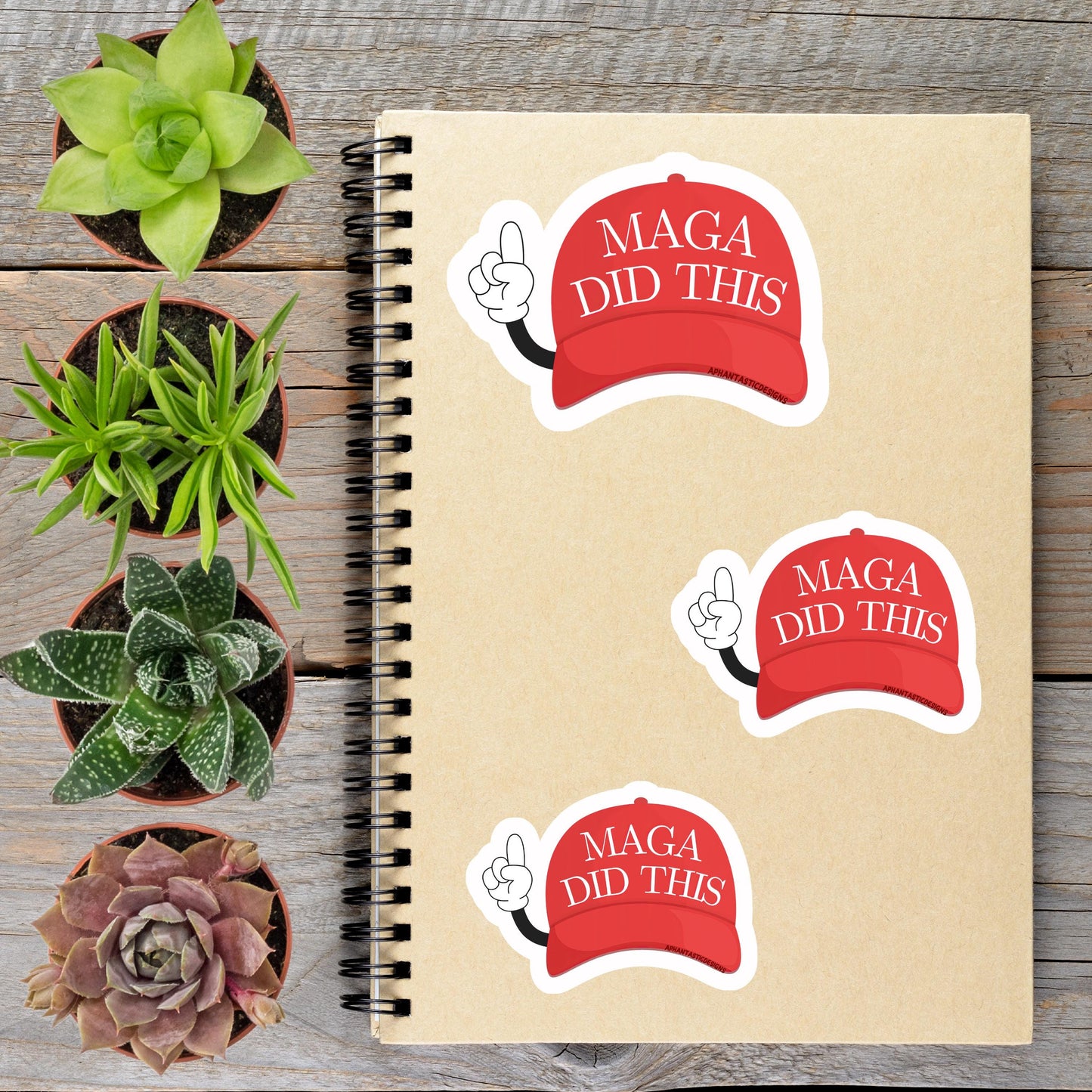 a spiral notebook with stickers on it, along with several potted plants arranged on a wooden surface.