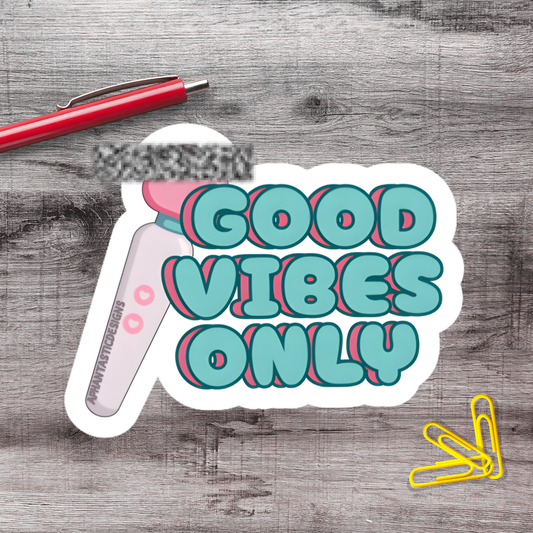 a sticker with the text "GOOD VIBES ONLY" in a stylized font, along with a pen and a pair of yellow paper clips.