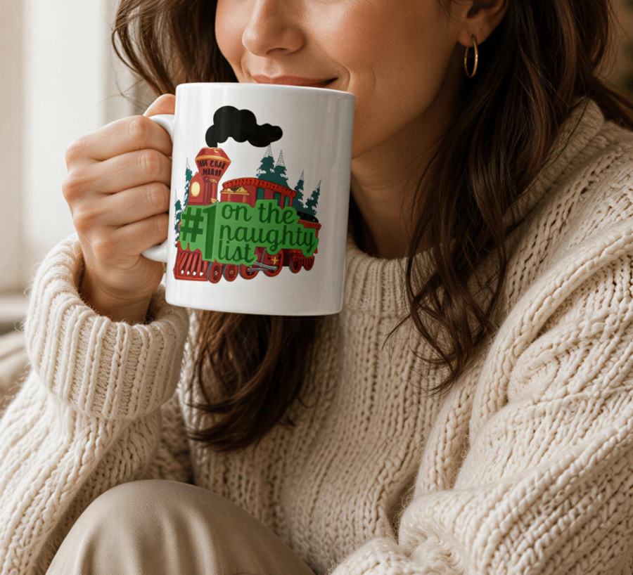 A woman in a white sweater sits on a couch, sipping from a mug with a Christmas-themed design. She is holding a book and has a plate of cookies nearby.