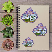 a notebook with stickers on it, along with several potted plants arranged on a wooden surface.