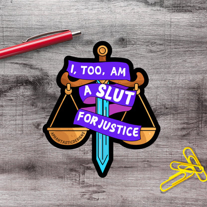 a sticker with a sword and scales, along with a red pen and yellow paper clips on a wooden surface.