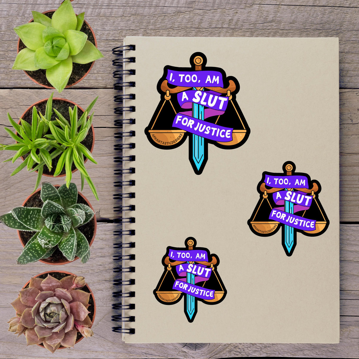a spiral notebook with stickers on it, along with several potted plants arranged on a wooden surface.