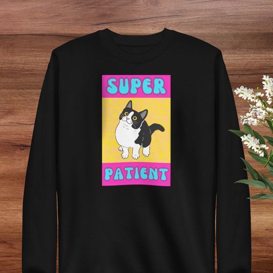 A black long-sleeved shirt with a graphic design featuring a cartoon cat and the text "SUPER PATIENT" in pink and blue colors.