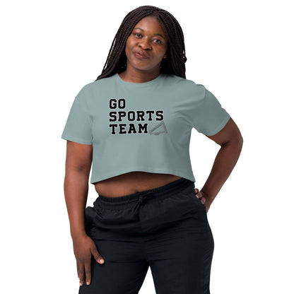 A woman wearing a light green crop top with the text "GO SPORTS TEAM" printed on it, standing with her hands on her hips.