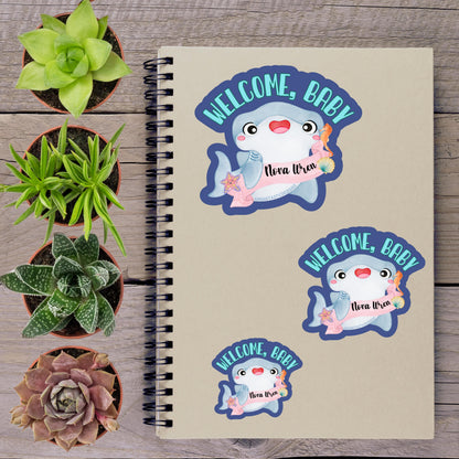 a spiral notebook with a welcome message sticker on the cover, surrounded by various potted plants and succulents.