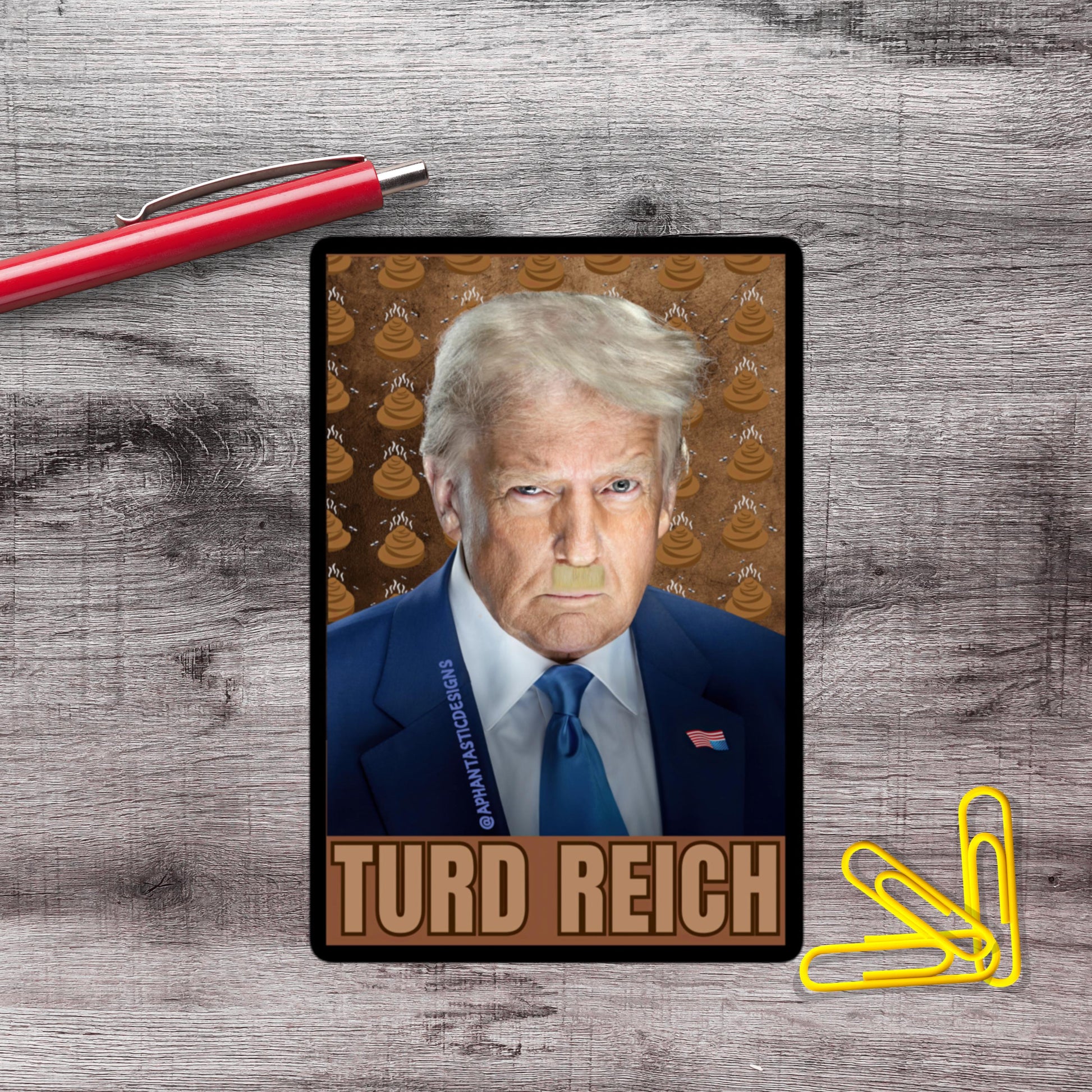 a man with blonde hair wearing a blue suit and tie, with a red pen and yellow paper clips on a wooden surface.