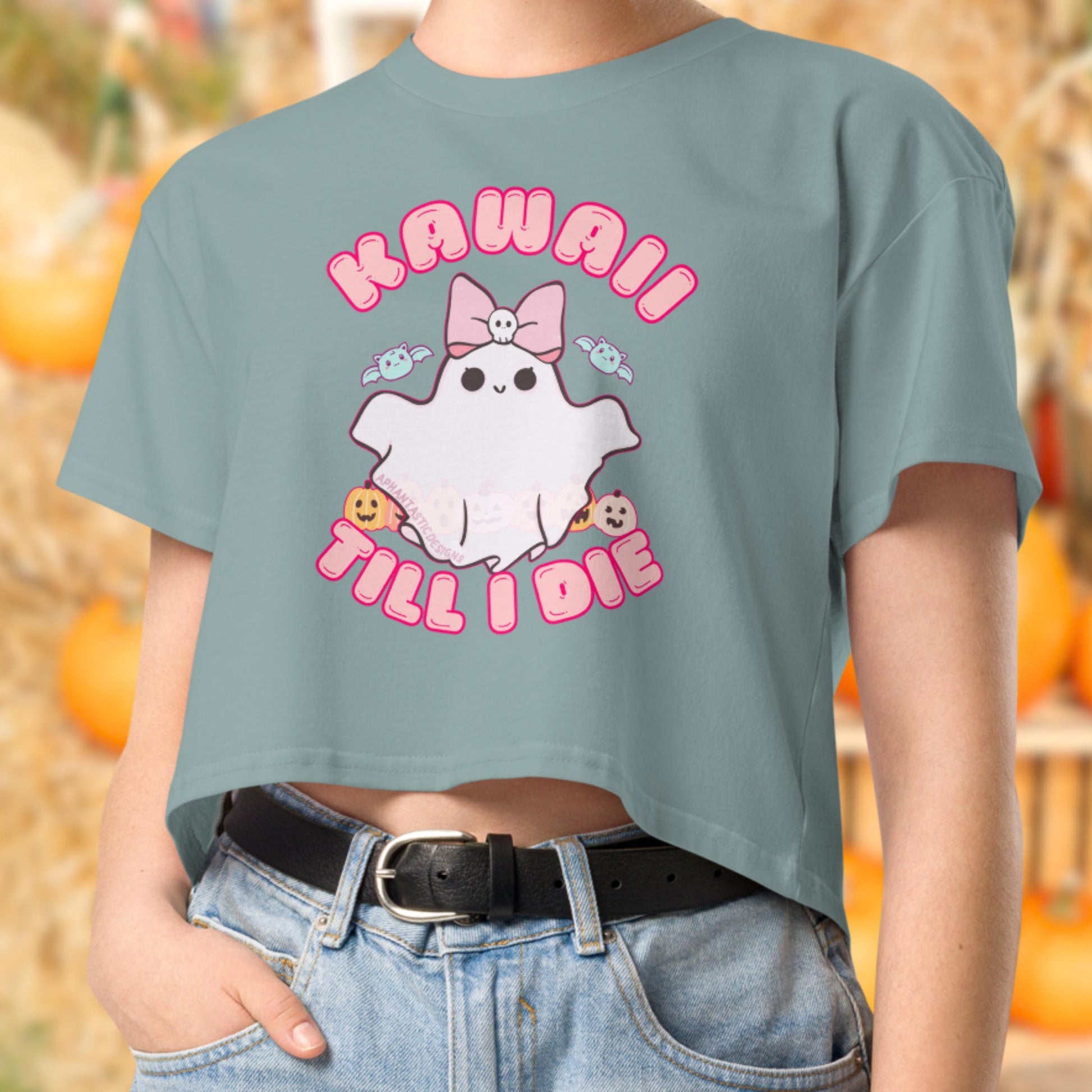 A person wearing a green t-shirt with a graphic design featuring a ghost character and the text "KAWAII TILL I DIE".