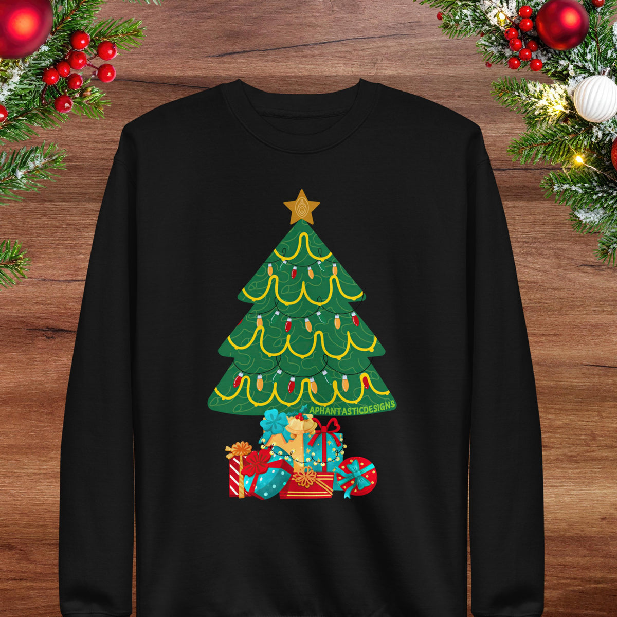 A black long-sleeved sweater with a Christmas tree design on it, surrounded by holiday decorations such as berries and ornaments.