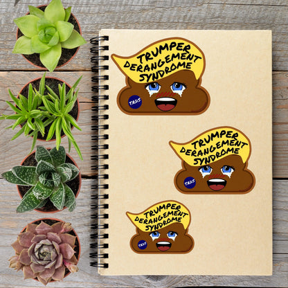 a spiral notebook with three cartoon stickers depicting a brown, anthropomorphized toilet with the text "TRUMPER DERANGE SYNDROME" written on it. The stickers are placed on the notebook, which is surrounded by potted plants on a wooden surface.