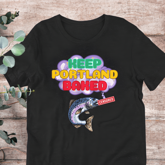 A black t-shirt with a colorful graphic design featuring a fish and the text "KEEP PORTLAND BAKED" along with a red "CENSORED" sticker.