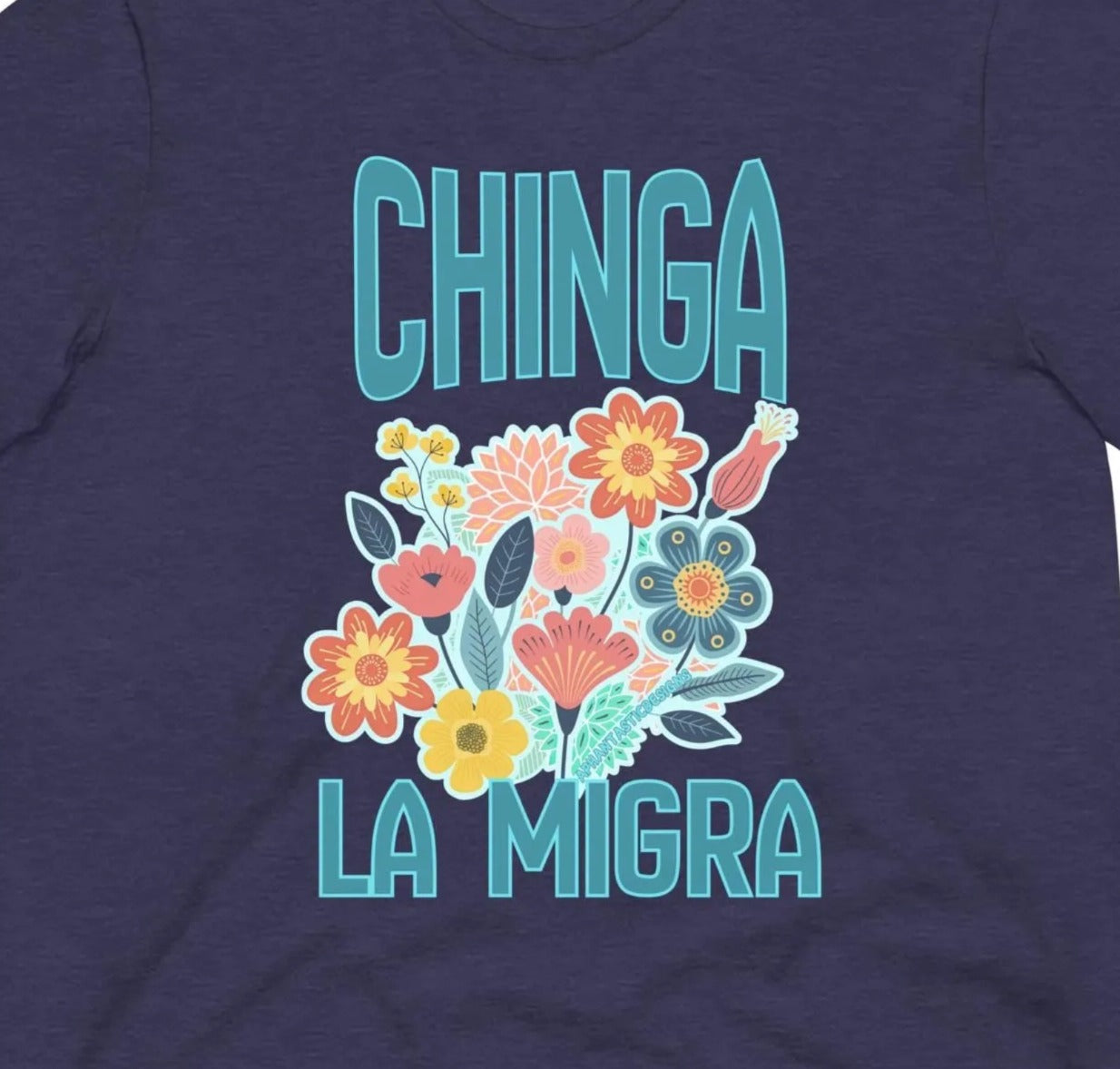 A dark blue t-shirt with a graphic design featuring colorful flowers and the text "CHINGA LA MIGRA" (which means "Migration" in English).