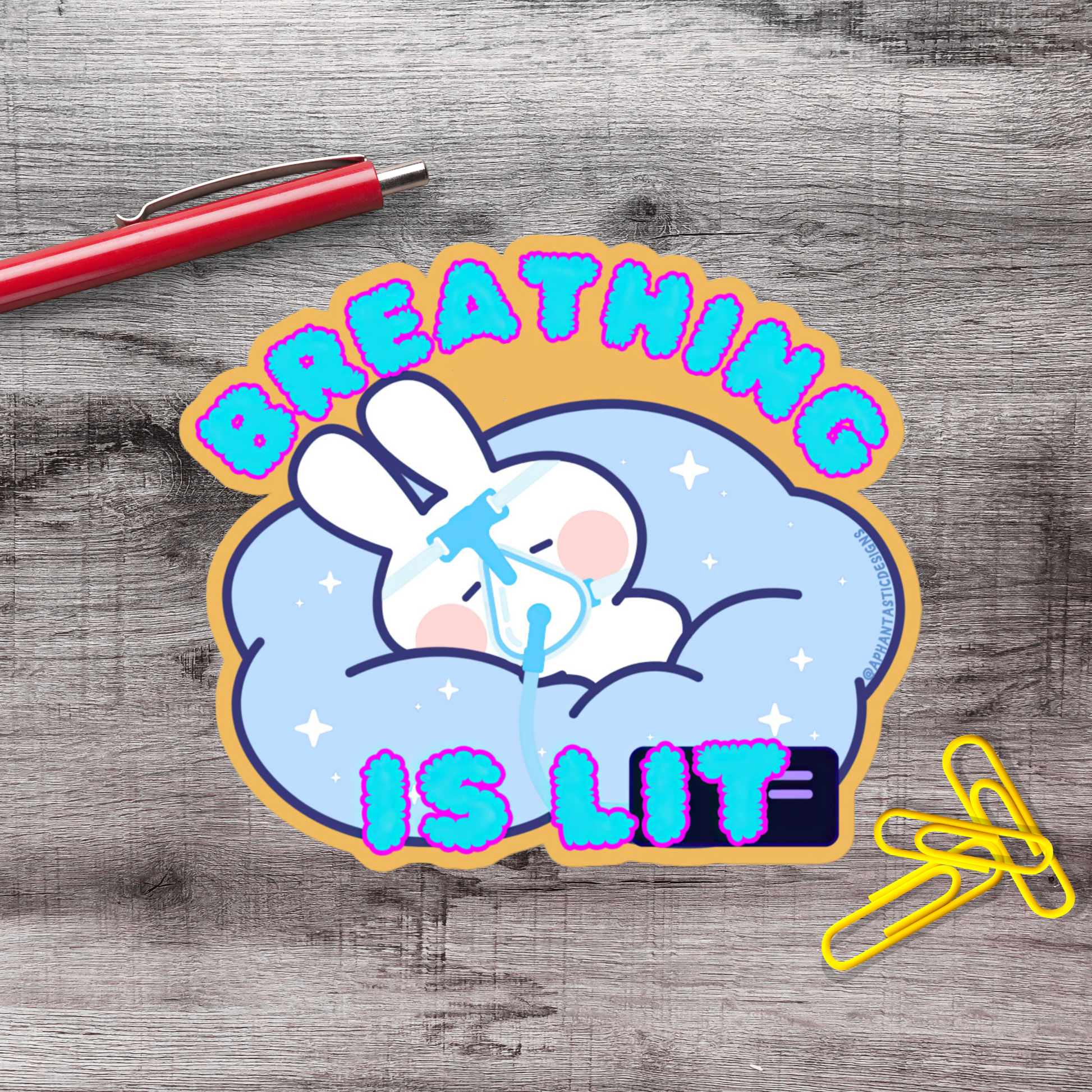 A sticker with a cartoon rabbit and the text "BREATHING IS LIT" on a wooden surface.