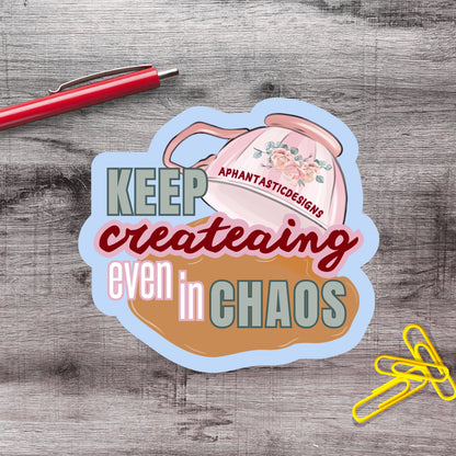 a sticker with the text "KEEP creating even in CHAOS" and an illustration of a teapot with flowers.