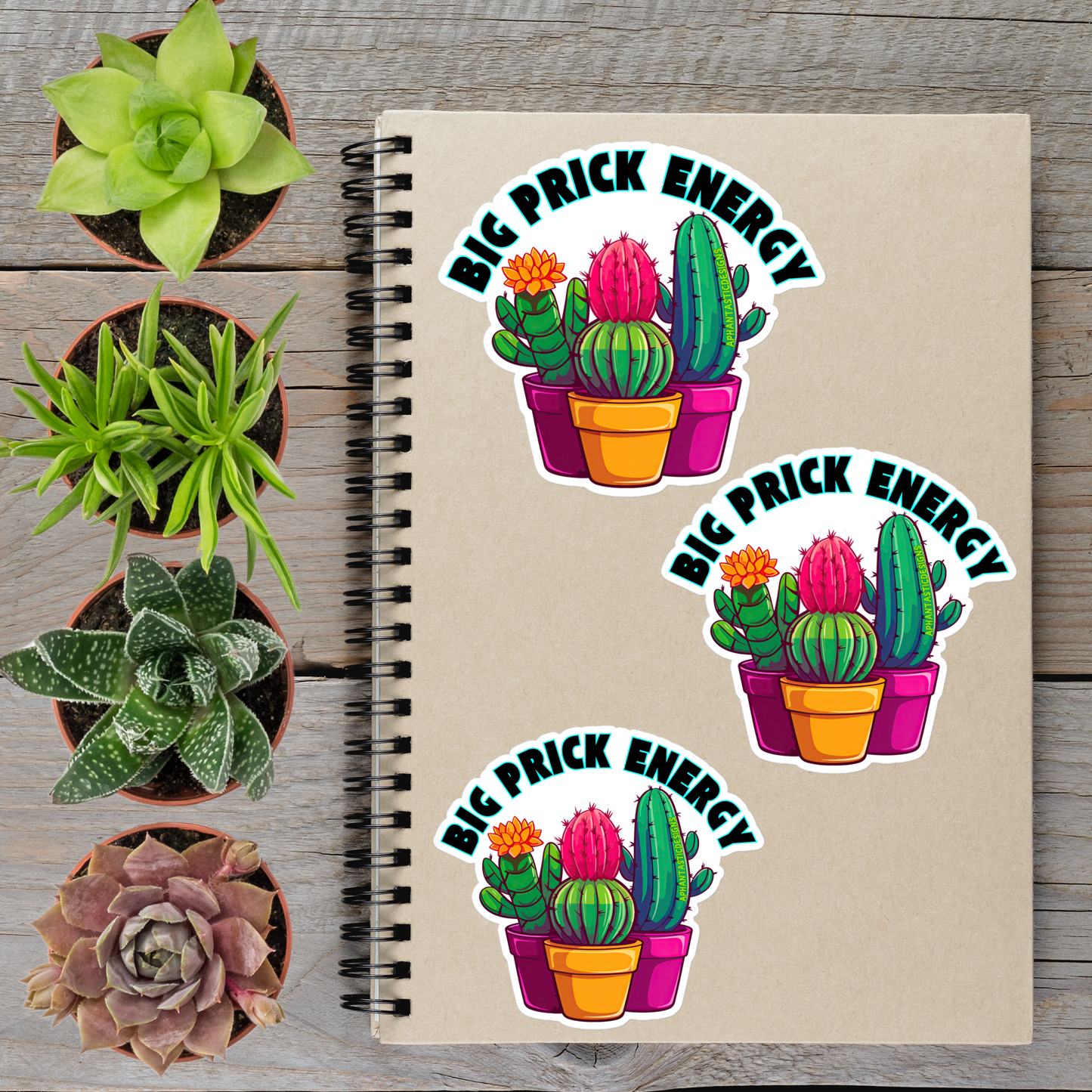 a spiral notebook with three stickers on it, each depicting a potted cactus with a flower. The stickers are arranged in a row on the notebook, and the background includes several potted plants.