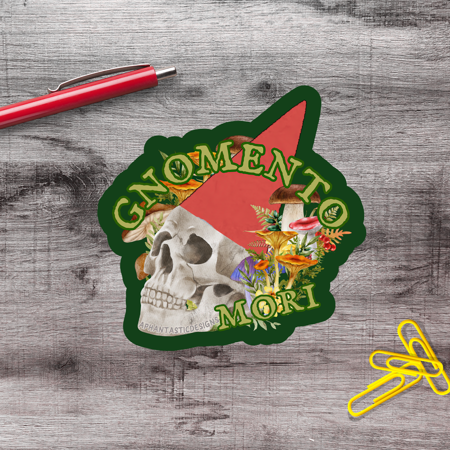 a sticker with a skull and mushrooms, along with the text "GNOMENTO MORI" and a red pen on a wooden surface.