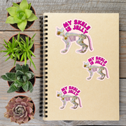 a spiral notebook with stickers on it, surrounded by potted plants.