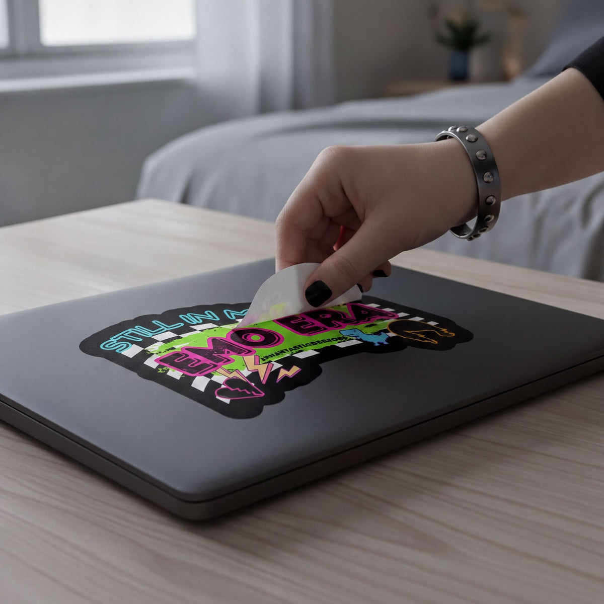 A person's hand is removing a sticker from a laptop.