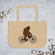 A beige tote bag with a graphic of a brown gorilla riding a bicycle on it, surrounded by white cotton balls.
