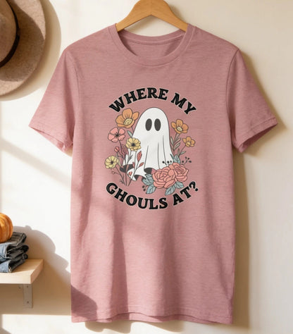 a pink t-shirt hanging on a wooden hanger, with a hat and two pumpkins placed on a shelf below it.