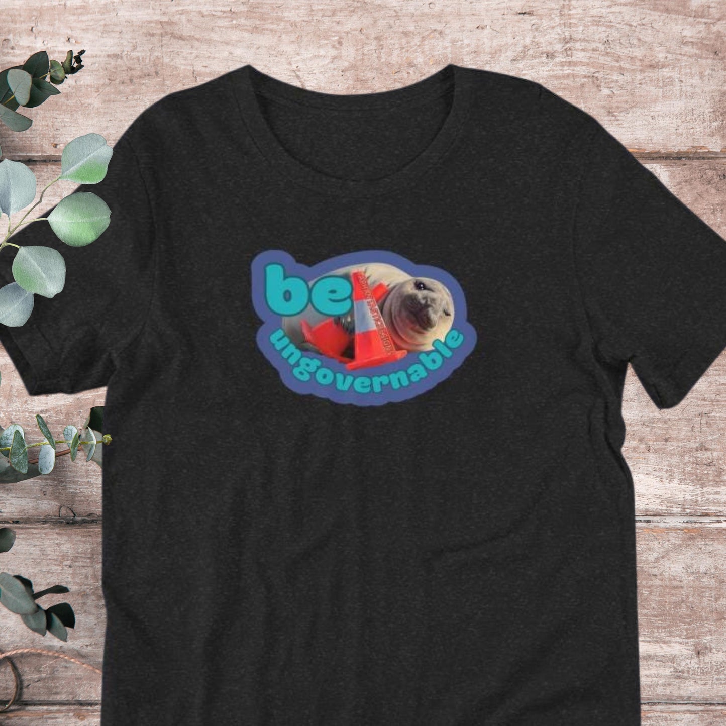 A black t-shirt with a graphic design featuring a seal and the text "be ungovernable" in a colorful, stylized font.