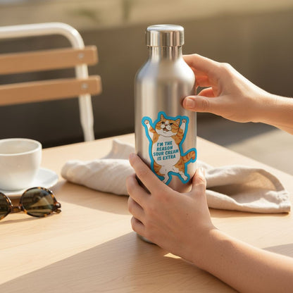 A person's hands are holding a metal water bottle with a sticker featuring a cat and the text "I'm the reason you're extra".