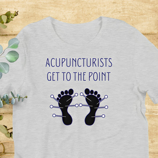 A gray t-shirt with the text "ACUPUNCTURISTS GET TO THE POINT" and a graphic of two feet with needles on them.