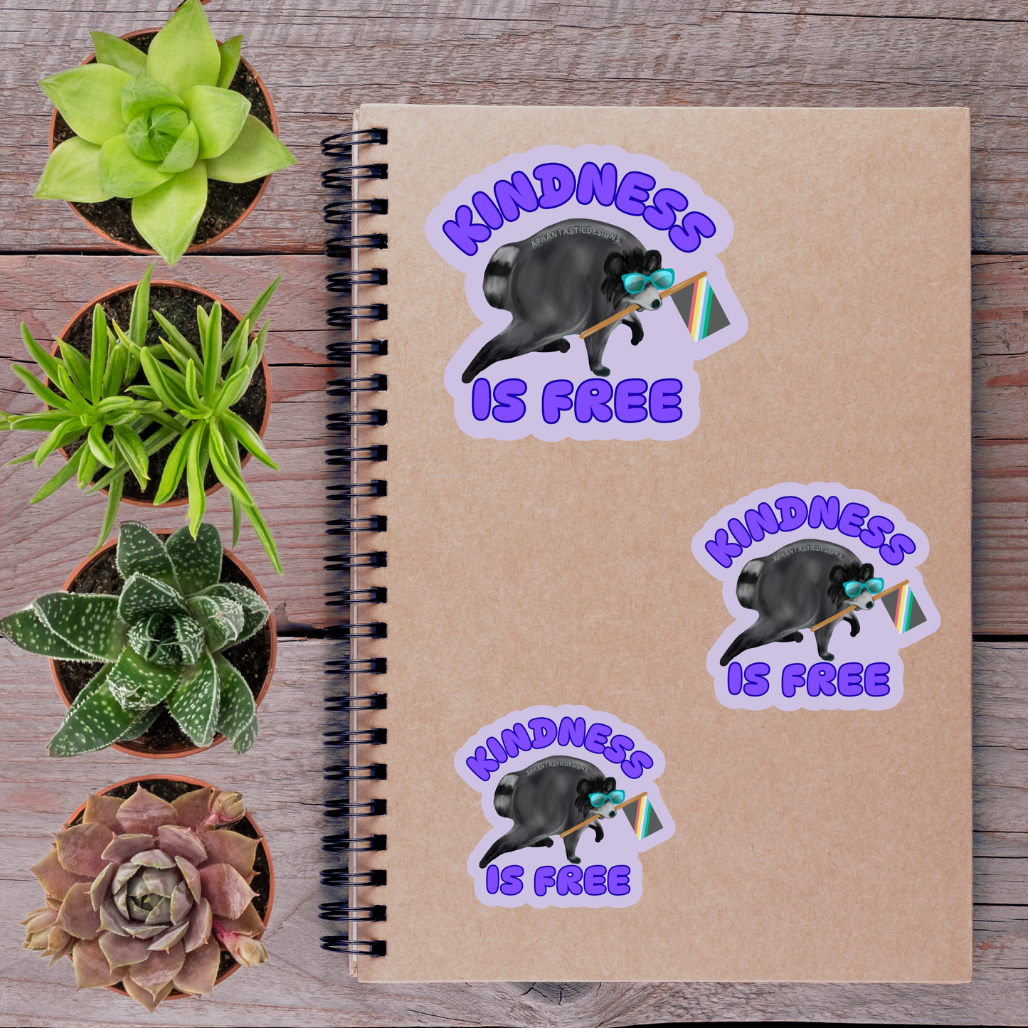 a notebook with stickers on it, surrounded by potted plants and a wooden surface.
