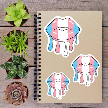 a spiral-bound notebook with three stickers of melting lips, surrounded by potted plants on a wooden surface.
