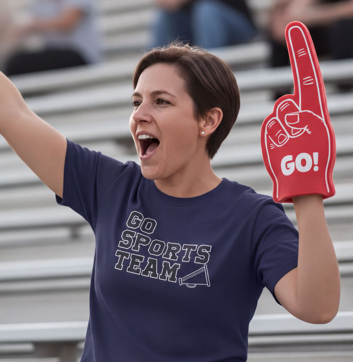A woman wearing a blue t-shirt with the text "GO SPORTS TEAM" cheering enthusiastically with a red foam finger that says "GO!".