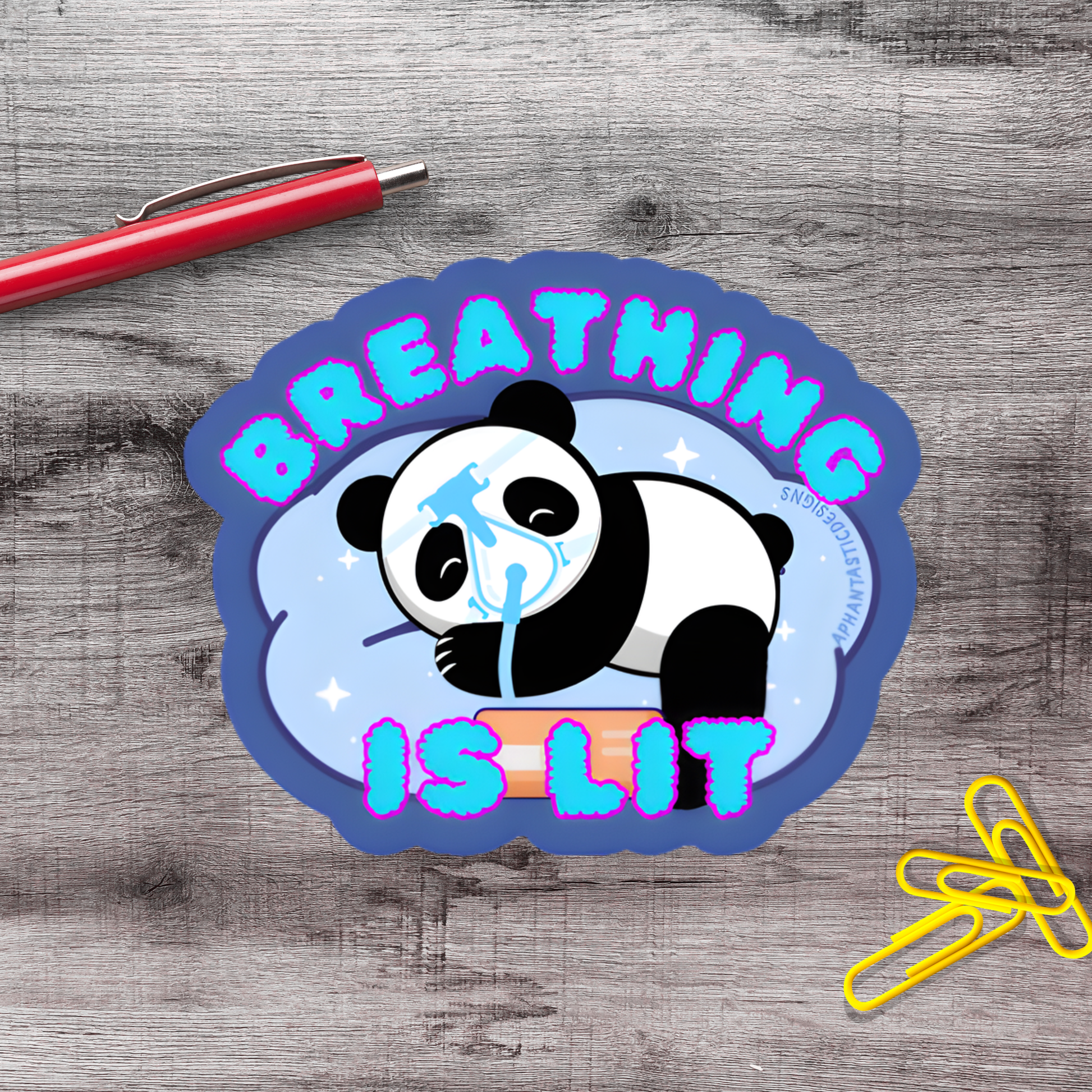 A sticker with a panda bear and the text "BREATHING IS LIT" on a wooden surface.