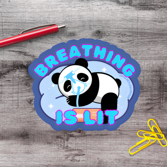 A sticker with a panda bear and the text "BREATHING IS LIT" on a wooden surface.