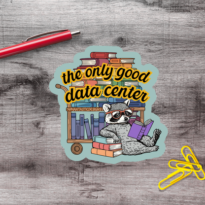 A sticker with a raccoon sitting on a bookshelf surrounded by books, with a red pen and yellow clips on a wooden surface.