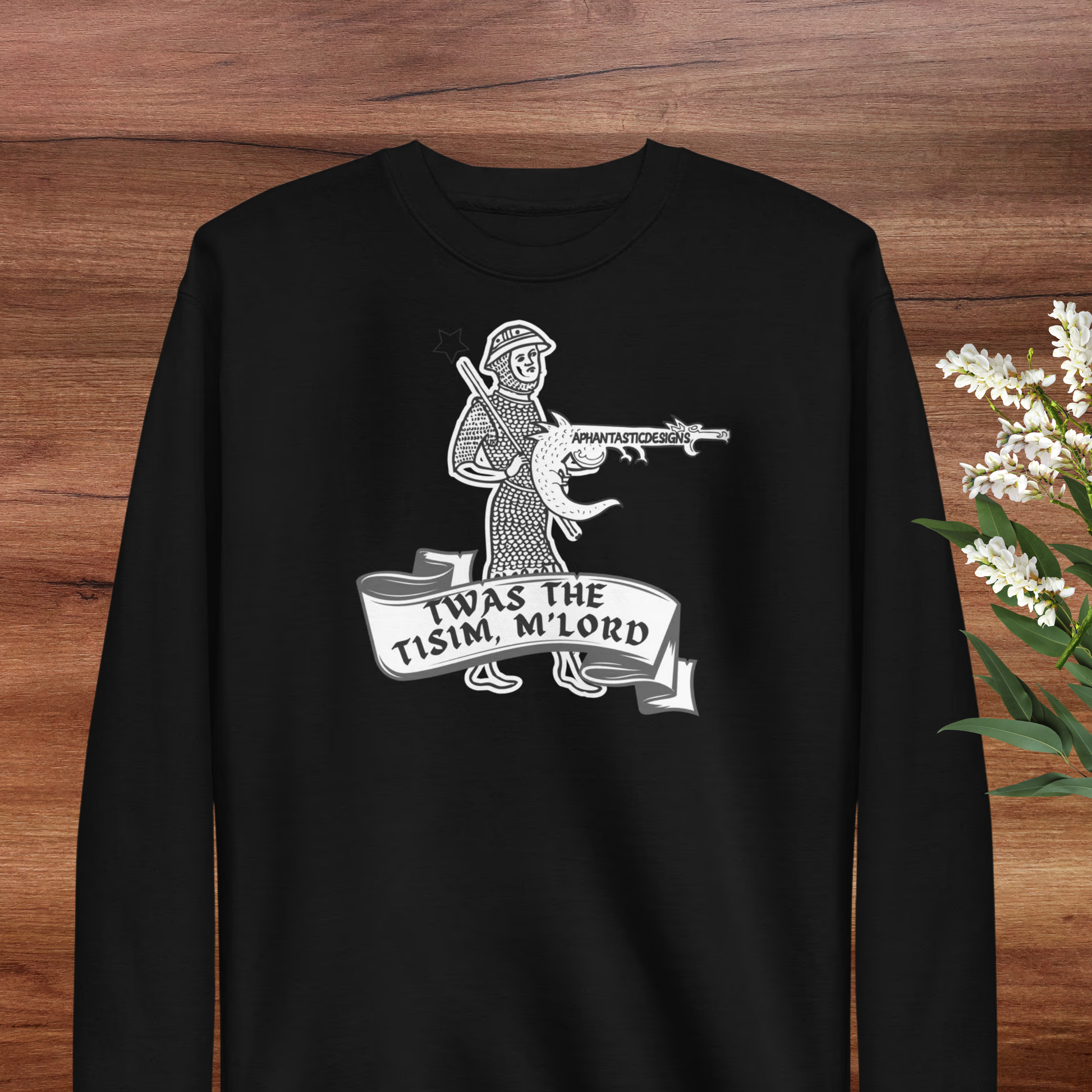 A black long-sleeved shirt with a graphic design depicting a person holding a gun and the text "TWAS THE TISIM. M LORD" below the image.