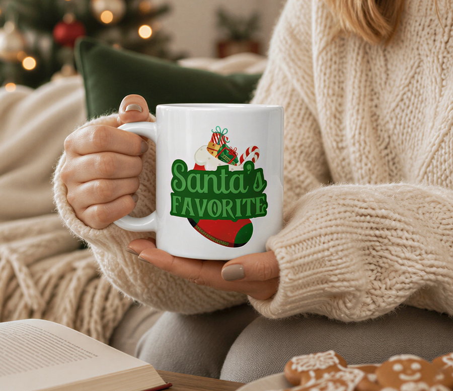 A person is sitting on a couch, holding a mug with the text "Santa's Favorite" printed on it, while a plate of gingerbread cookies is nearby.
