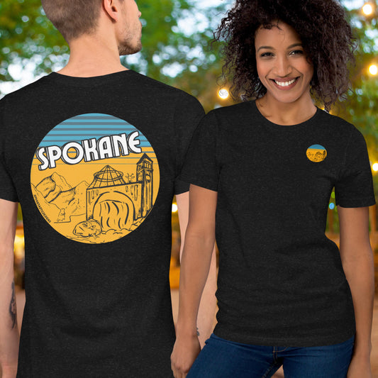 A man and a woman are wearing black t-shirts with a graphic design featuring a yellow and blue illustration of a city skyline.