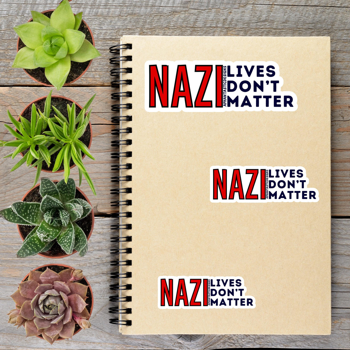 a spiral notebook with stickers on it, along with four potted plants arranged on a wooden surface.