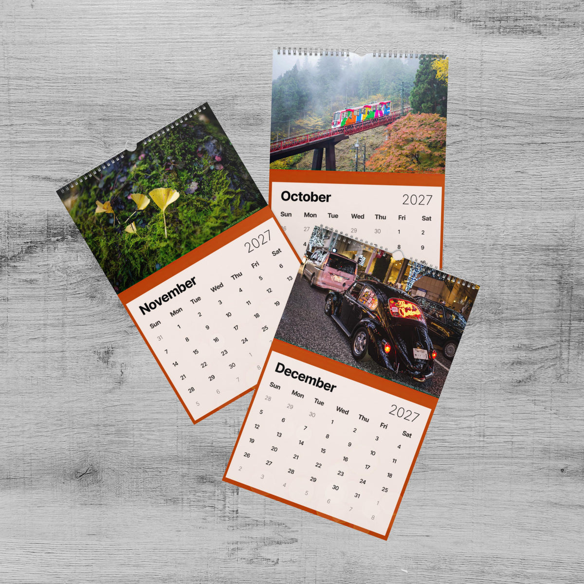 The image is a three-page calendar with various photographs, including a bridge, flowers, and a car. The calendar is set against a wooden background.