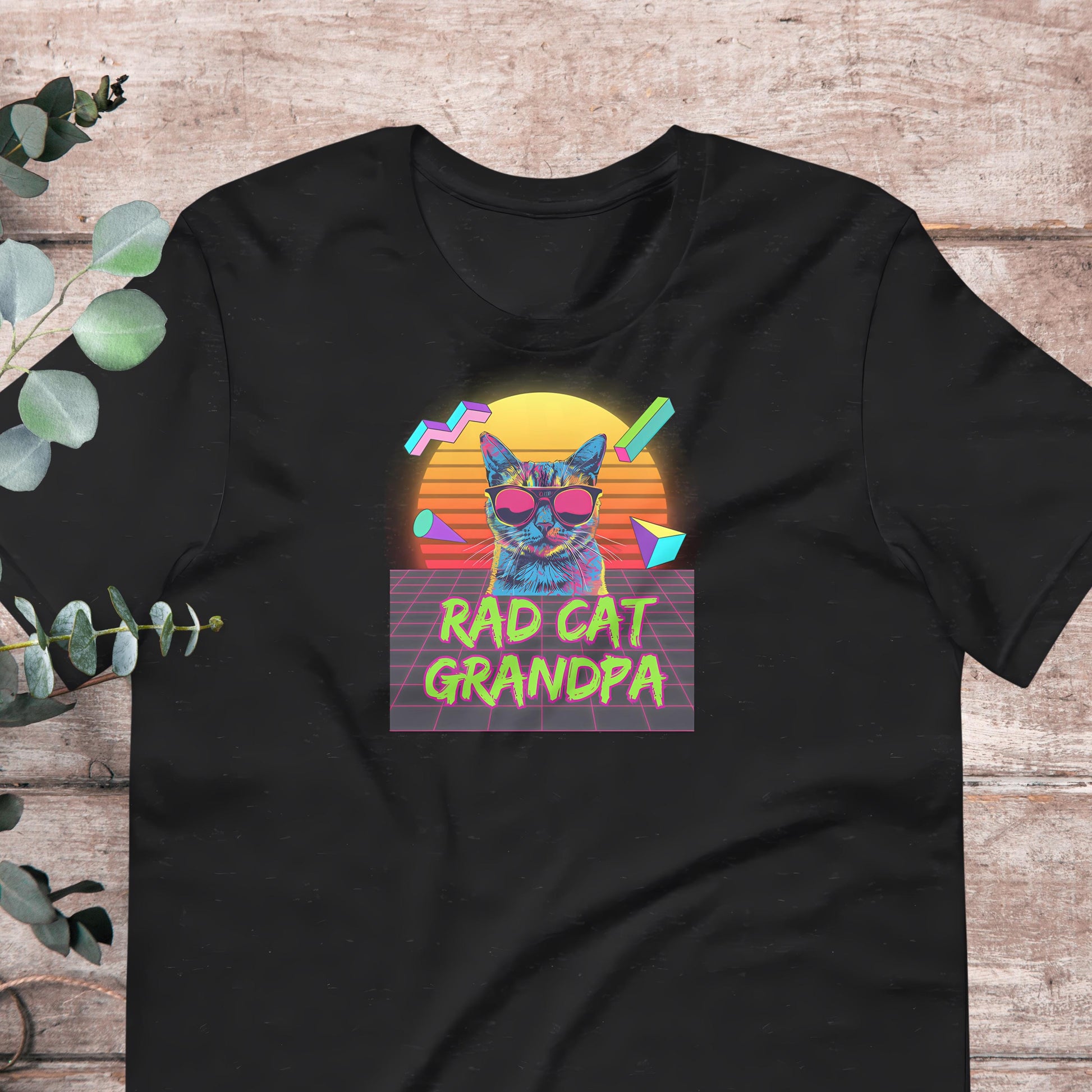 A black t-shirt with a colorful graphic design featuring a cat wearing sunglasses and the text "RAD CAT GRANDPA" against a retro-style background.