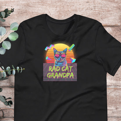 A black t-shirt with a colorful graphic design featuring a cat wearing sunglasses and the text "RAD CAT GRANDPA" against a retro-style background.