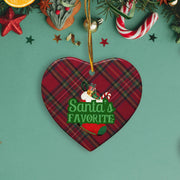 A heart-shaped ornament with a plaid pattern and the text "Santa's Favorite" is hanging on a Christmas tree.