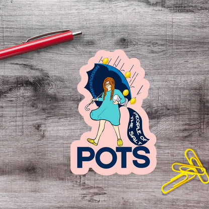 A sticker with a cartoon illustration of a woman holding an umbrella and the text "POTS" is placed on a wooden surface next to a red pen and yellow paper clips.