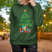 A woman wearing a green sweater with a Christmas tree design on it, standing in front of a blurred background with lights.