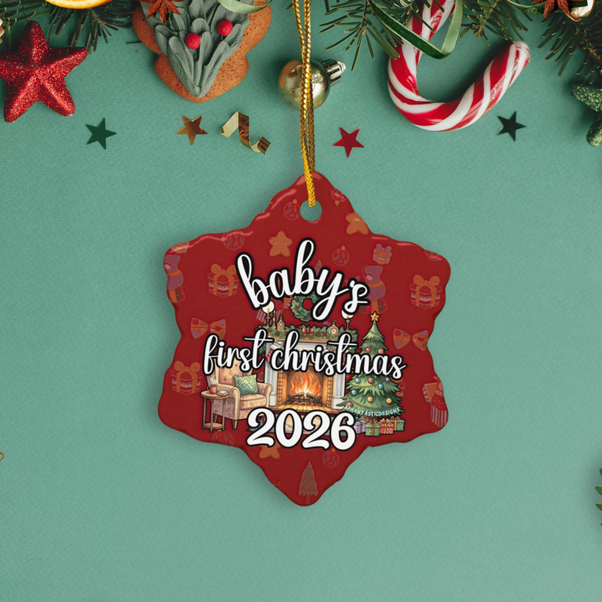 A red star-shaped ornament with the text "baby's first christmas 2026" is hanging on a Christmas tree, surrounded by various holiday decorations such as stars, candy canes, and a pine tree.