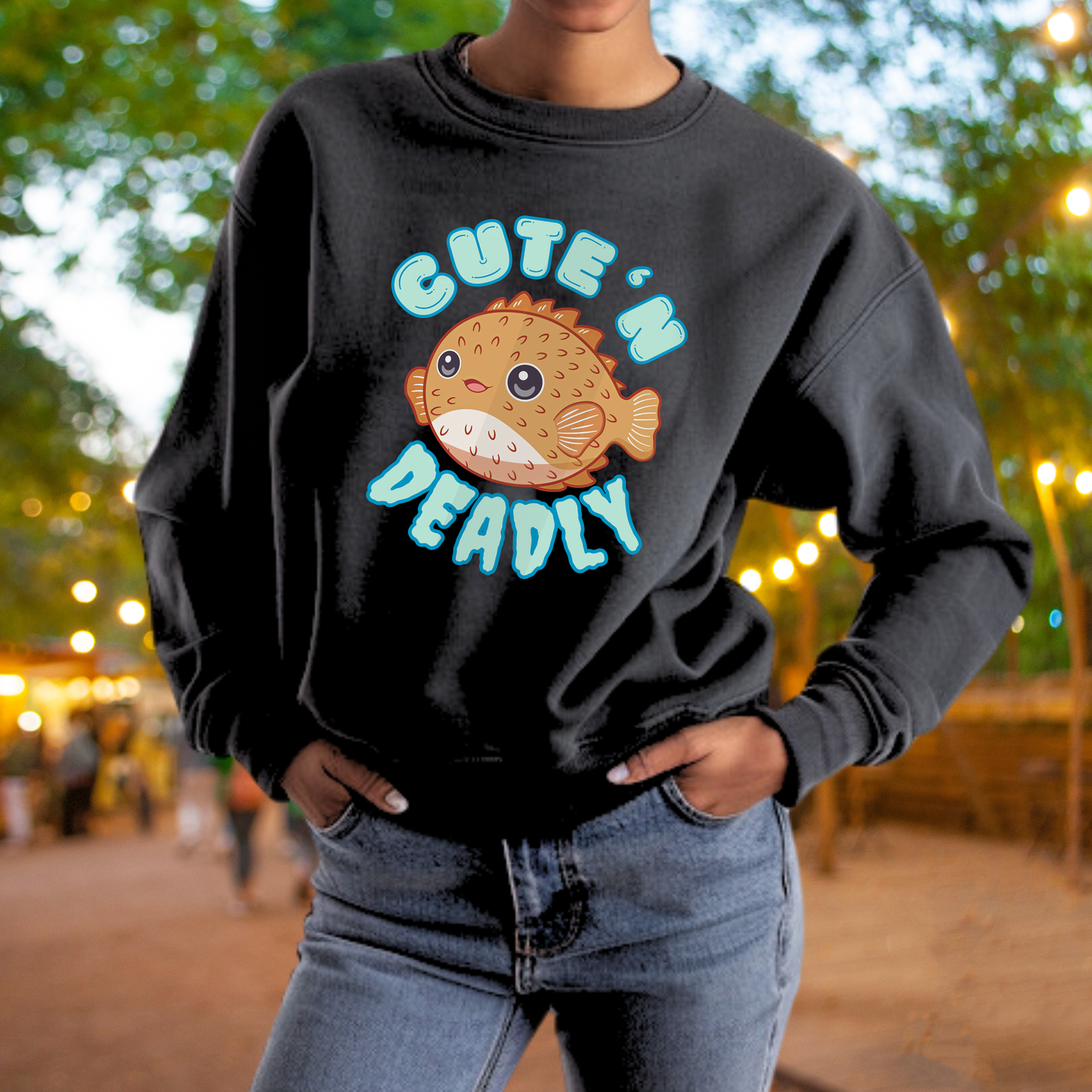 A person wearing a black sweatshirt with a graphic of a fish and the text "CUTE 'N DEADLY" printed on it.